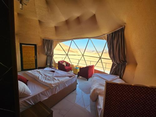 a bedroom with two beds and a large window at Russell desert luxury camp in Wadi Rum