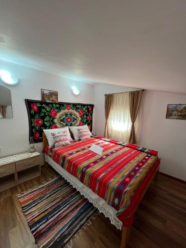 a bedroom with a large bed with a colorful blanket at Casa Vio in Nehoiu