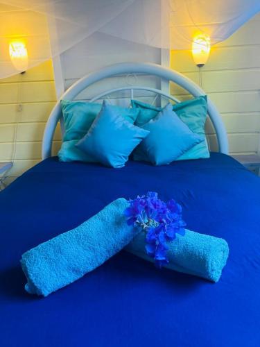 a blue bed with blue pillows and blue flowers on it at Bungalow Atoll Sainte-Anne in Sainte-Anne