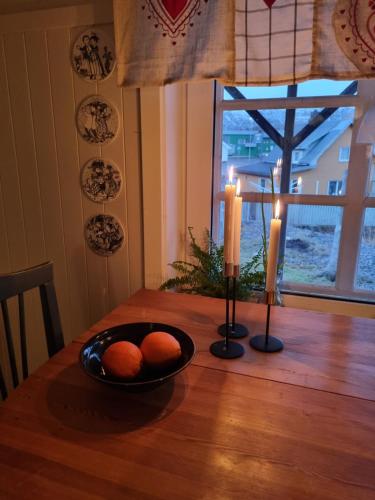 a table with two candles and a bowl of oranges on it at Huset i Stamsund in Rishaugen