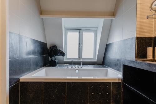 a bath tub in a bathroom with a window at Hotel Roemer Amsterdam in Amsterdam