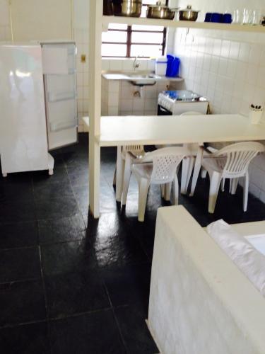 a kitchen with a table and chairs and a refrigerator at Vila Giulia in Maresias