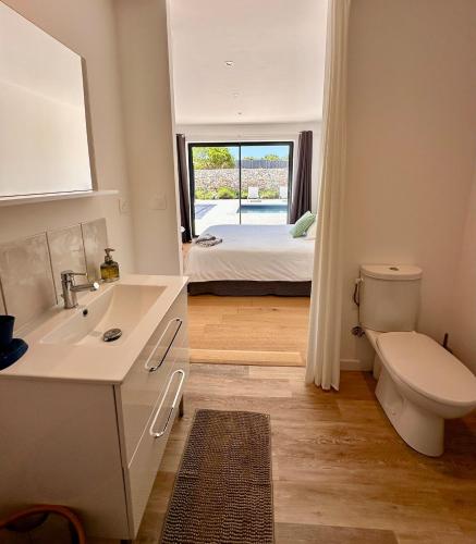 une salle de bain avec un lavabo et des toilettes et un lit dans l'établissement Villa Gioia- Charme et sérénité, à Bonifacio