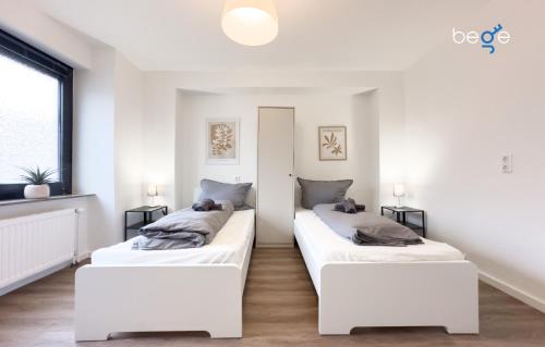 two beds in a room with white walls at BEGE APARTMENTS ConnectPoint in Nettetal