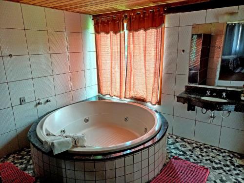 La salle de bains est pourvue d'une baignoire et d'un miroir. dans l'établissement Pousada Chalés Vista da Serra, à Visconde de Mauá