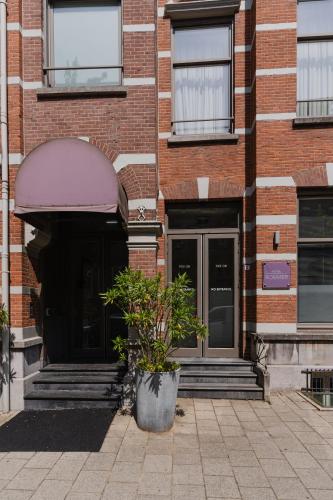 an entrance to a brick building with a plant in a pot at Hotel Roemer Amsterdam in Amsterdam