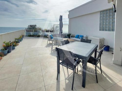 un patio avec une table et des chaises et l'océan dans l'établissement 3 chambres internet stationnement situation unique en 1ere ligne mer, à Sète