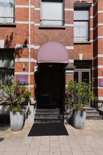 a black door in a brick building with two potted plants at Hotel Roemer Amsterdam in Amsterdam