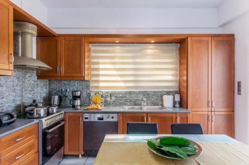 a kitchen with wooden cabinets and a sink and a table at White House Chersonisos with Private swimming pool in Limín Khersonísou