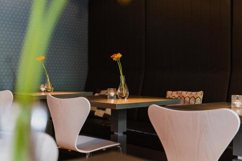 two tables with chairs and vases with flowers on them at Hotel Roemer Amsterdam in Amsterdam