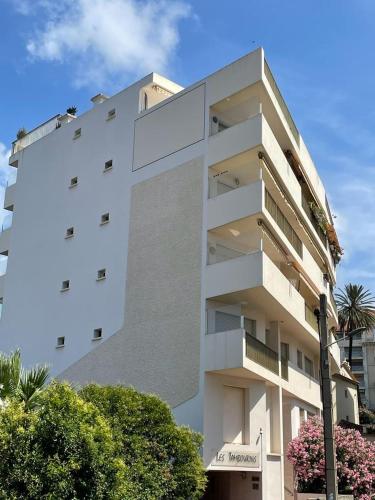 un grand bâtiment blanc avec des arbres devant lui dans l'établissement Mistral Seaside Studio - 200m de la Plage, à Cannes