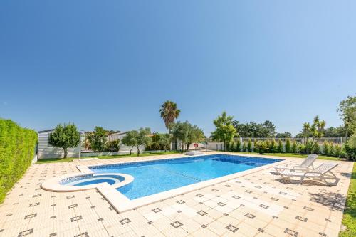 a swimming pool in a yard with two chairs next to it at Magalhães Village by LovelyStay in Santo António da Charneca