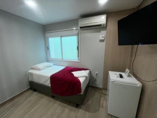a small bedroom with a bed and a television at Hotel Morada Del Este in Canoas