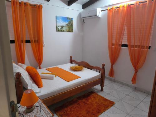 Zimmer mit einem Bett und orangefarbenen Vorhängen in der Unterkunft Villa de la montagne in Pointe-Noire