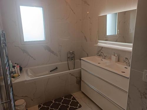 La salle de bains blanche est pourvue d'un lavabo et d'une baignoire. dans l'établissement Le Mans spécial 24h, à Changé