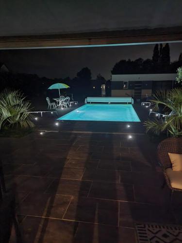 - une piscine avec une table et un parasol la nuit dans l'établissement Le Mans spécial 24h, à Changé