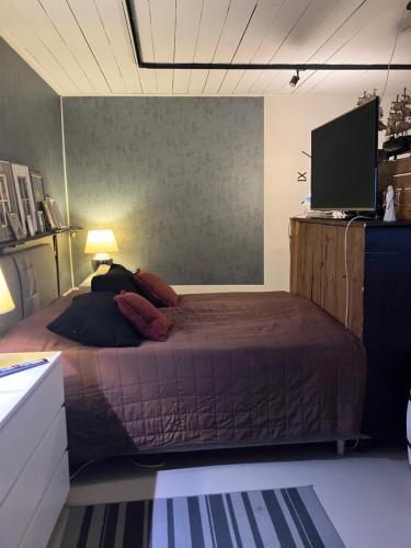 a bedroom with a bed and a flat screen tv at Vanha Ravintola Ölvin Suolatorilla - Vanhan Kanttorilan yhteydessä in Lovisa