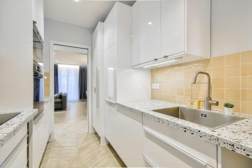 une cuisine avec des armoires blanches et un évier dans l'établissement Stylish and New 2BR Flat in the Heart of Paris, à Paris