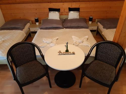 a room with two beds and a white table with two chairs at Art Galéria Apartman in Gyenesdiás