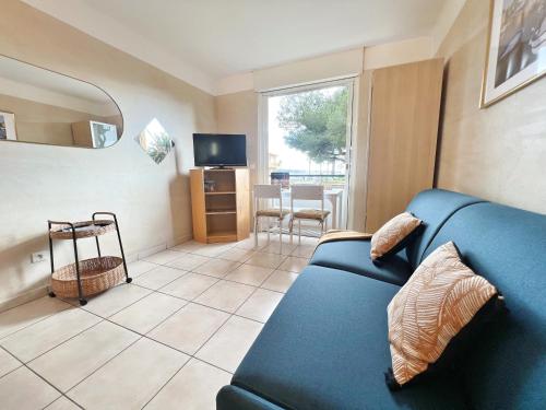 un salon avec un canapé bleu et une télévision dans l'établissement Sanary, Studio vue mer, à deux pas des plages et du centre ville, à Sanary-sur-Mer