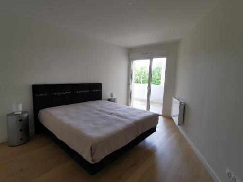 une chambre avec un grand lit dans une pièce blanche dans l'établissement Olympe, à La Rochelle