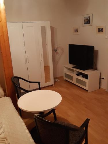 a living room with a table and a television at Art Galéria Apartman in Gyenesdiás