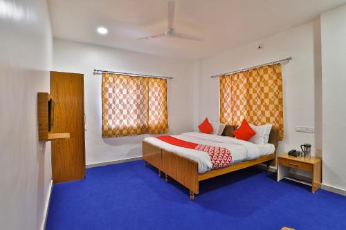 a bedroom with a bed with blue carpet and orange curtains at Hotel O Milan Party Hall in Vadodara