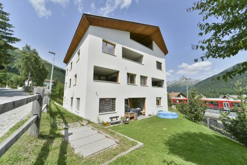 a white house with a green yard at Chesa Arpiglia - Zuoz in Zuoz