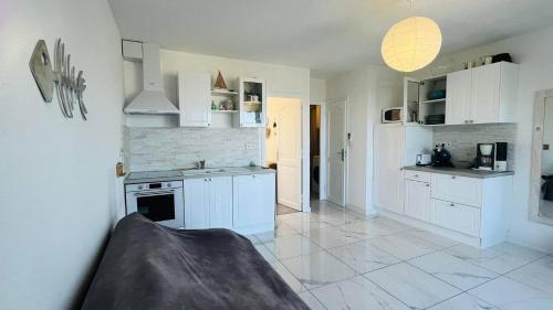 une cuisine avec des armoires blanches et une cuisinière dans l'établissement Appartement Les Rochers CALVI, à Calvi