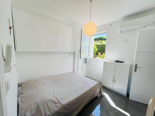 une chambre blanche avec un lit et une fenêtre dans l'établissement Appartement Les Rochers CALVI, à Calvi