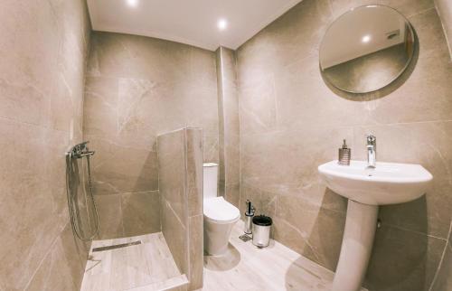a bathroom with a sink and a toilet and a mirror at Bloom Garden Apartments in Ierissos