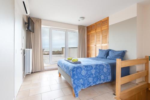 a bedroom with a blue bed and a large window at Nori TV in Ostend