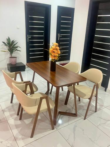 a wooden dining table with chairs and a vase with flowers at Résidence Turpin in Toubab Dialaw