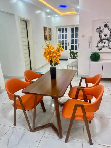 a dining room with a wooden table and orange chairs at Résidence Turpin in Toubab Dialaw