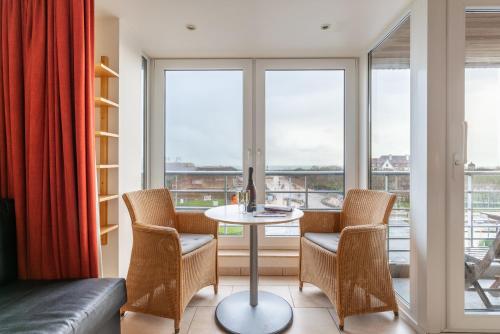 a living room with a table and chairs and windows at Nori TV in Ostend