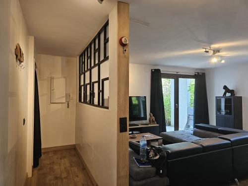 un salon avec un canapé noir et une télévision dans l'établissement Joli logement spacieux, à Annecy