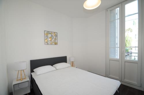 une chambre blanche avec un lit et une fenêtre dans l'établissement Les Trois Mai, à Cannes