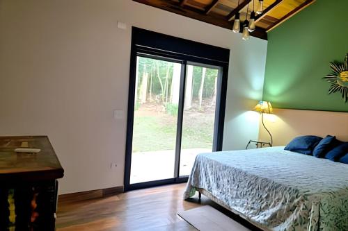 a bedroom with a bed and a large sliding glass door at Casa, Pequeno Bosque e vista para Horizonte in Ibiúna