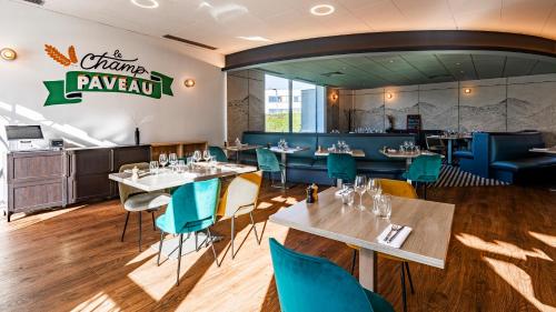 a dining room with tables and blue chairs at Novotel Reims Tinqueux in Reims