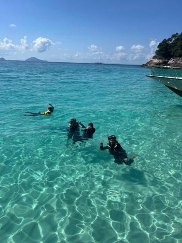 three people laying in the water in the ocean at Merang Jetty Homestay in Baroh Pahlawan