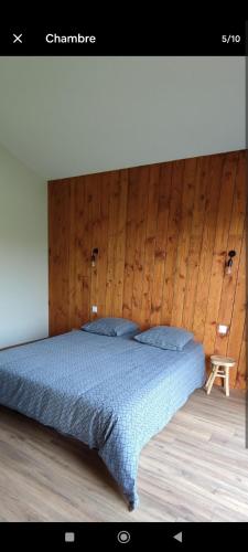 ein Schlafzimmer mit einem Bett mit einer Holzwand in der Unterkunft Le Chalet d'Agen in Boé