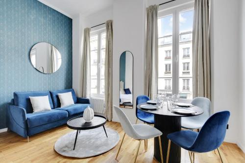 un salon avec un canapé bleu, une table et des chaises dans l'établissement CMG Résidence Bastille - Saint Antoine, à Paris