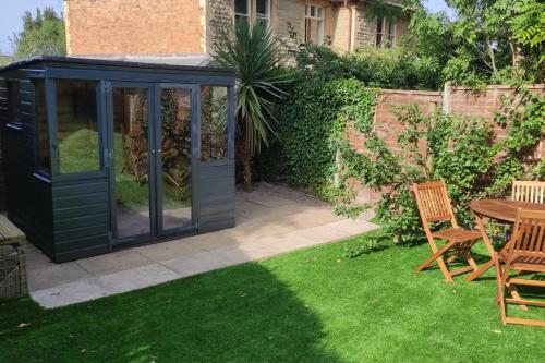 a greenhouse in a garden with a table and chairs at Elegant Malvhina Retreat on the Malvern Hills in Great Malvern