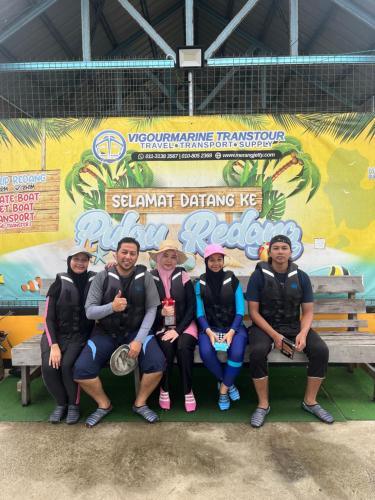 a group of people sitting on a bench in front of a wall at Merang Jetty Homestay in Baroh Pahlawan