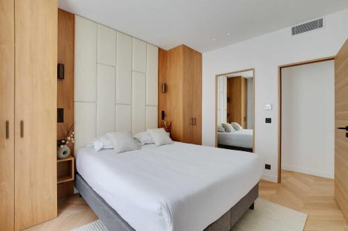 une chambre avec un grand lit blanc et un miroir dans l'établissement Appartement Moderne - 3BR-6P - Montorgueil, à Paris