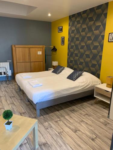 - une chambre avec un grand lit et des murs jaunes dans l'établissement Trankil'Apparts Gare, à Saint-Quentin