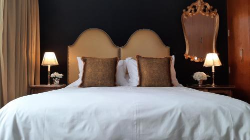 a bedroom with a large white bed with two lamps at Ana Frank Boutique Hotel in Lima