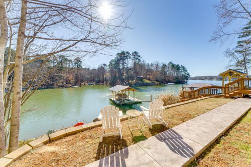 a dock with two chairs and a boat on the water at Fall Escape on Lookout Shoals Lake with Game Room! in Sharon
