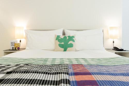 a bed with white sheets and a cactus pillow at Greulich Design & Boutique Hotel in Zürich