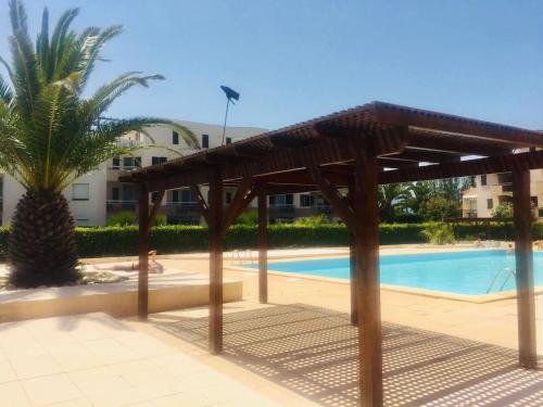 un pavillon en bois devant une piscine dans l'établissement Joli studio les pieds dans l'eau avec piscine, à Saint Cyprien Plage
